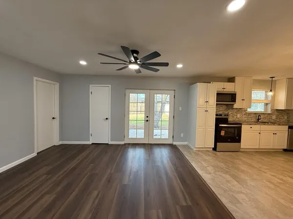a view of an empty room with window and wooden floor
