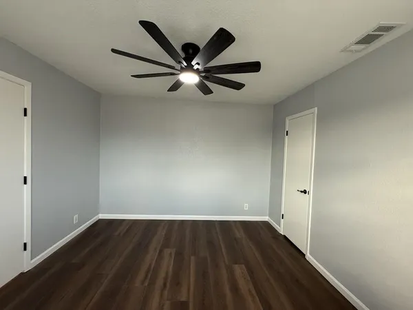 a view of an empty room with window and wooden floor