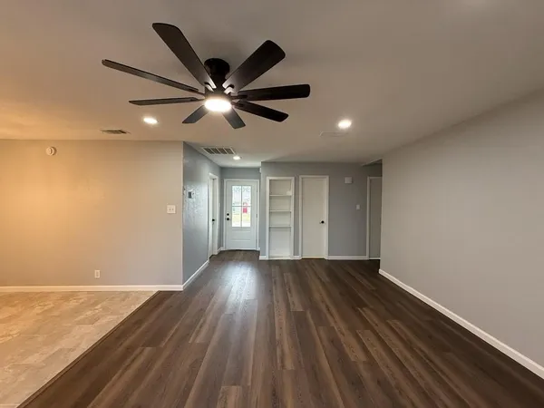 a view of an empty room with wooden floor and a window