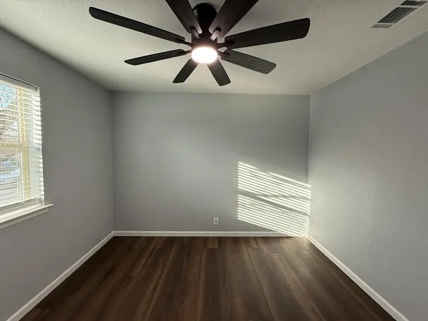 a view of an empty room with wooden floor and a window