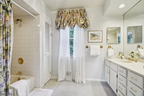 a spacious bathroom with a double vanity sink a mirror a bathtub and shower