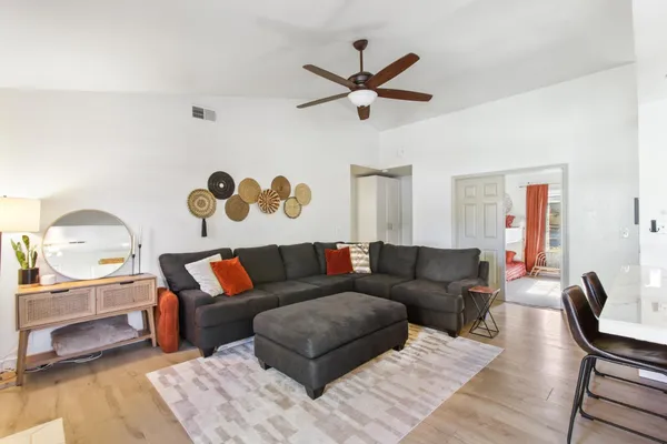 a living room with a couch and a dining table with wooden floor