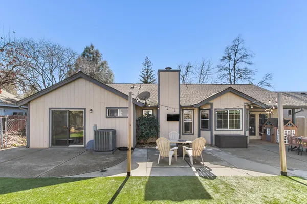a view of a house with a yard chairs and table in patio