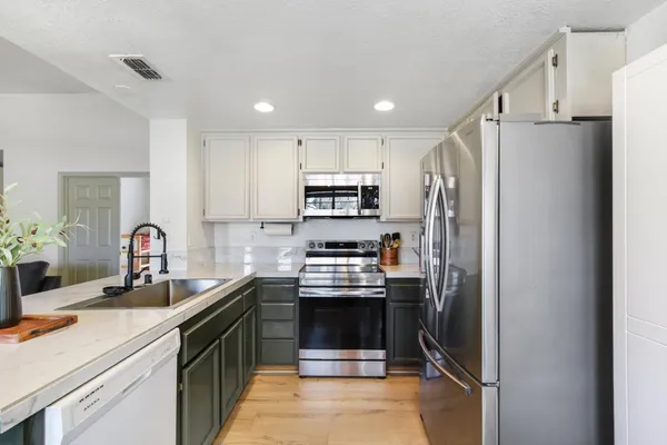 a kitchen with stainless steel appliances a refrigerator sink and white cabinets