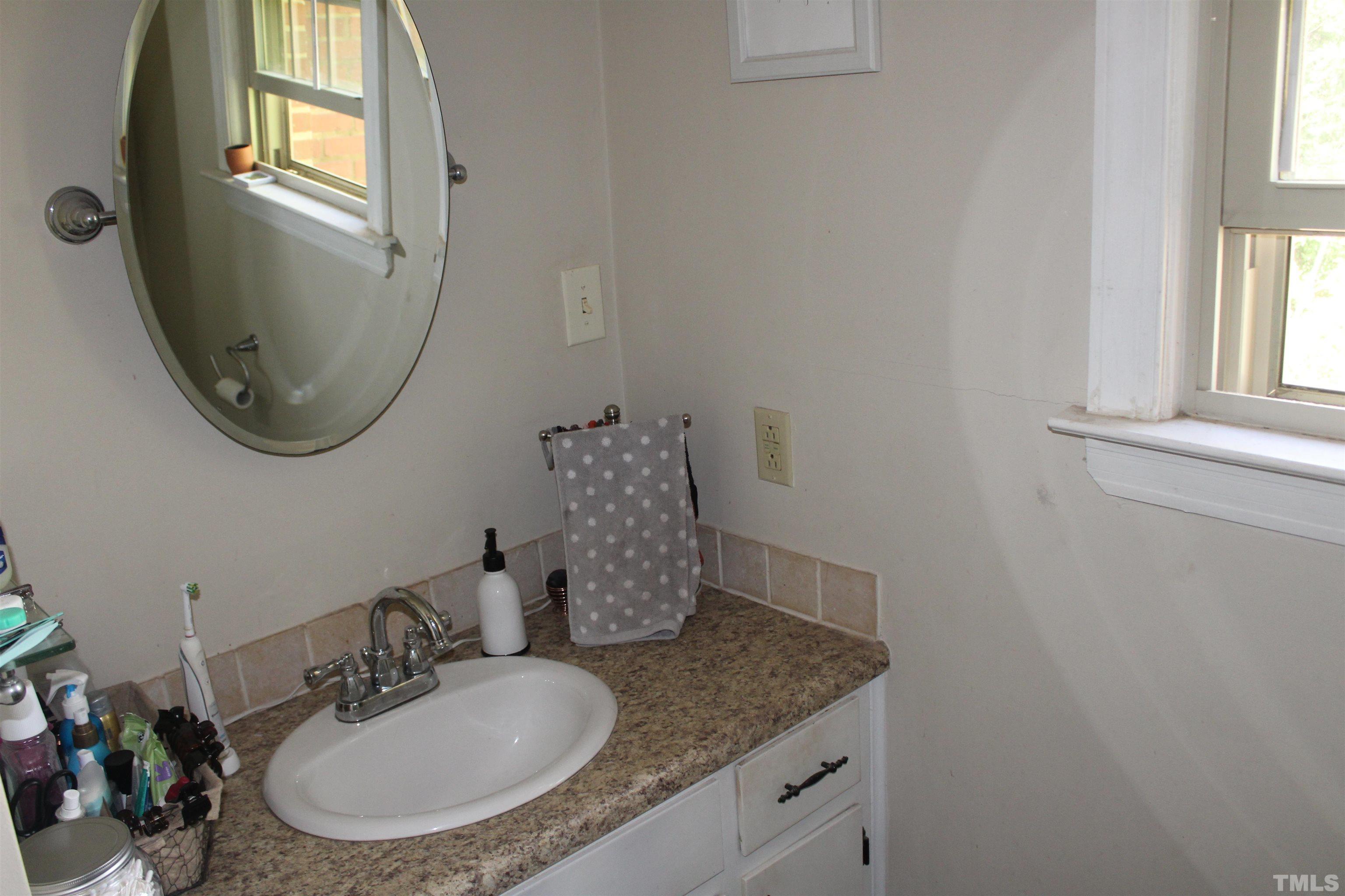 2248 The Circle, Unit 2 Raleigh, NC 27608 - Photo 10 of 21 a bathroom with a granite countertop sink a mirror and a window