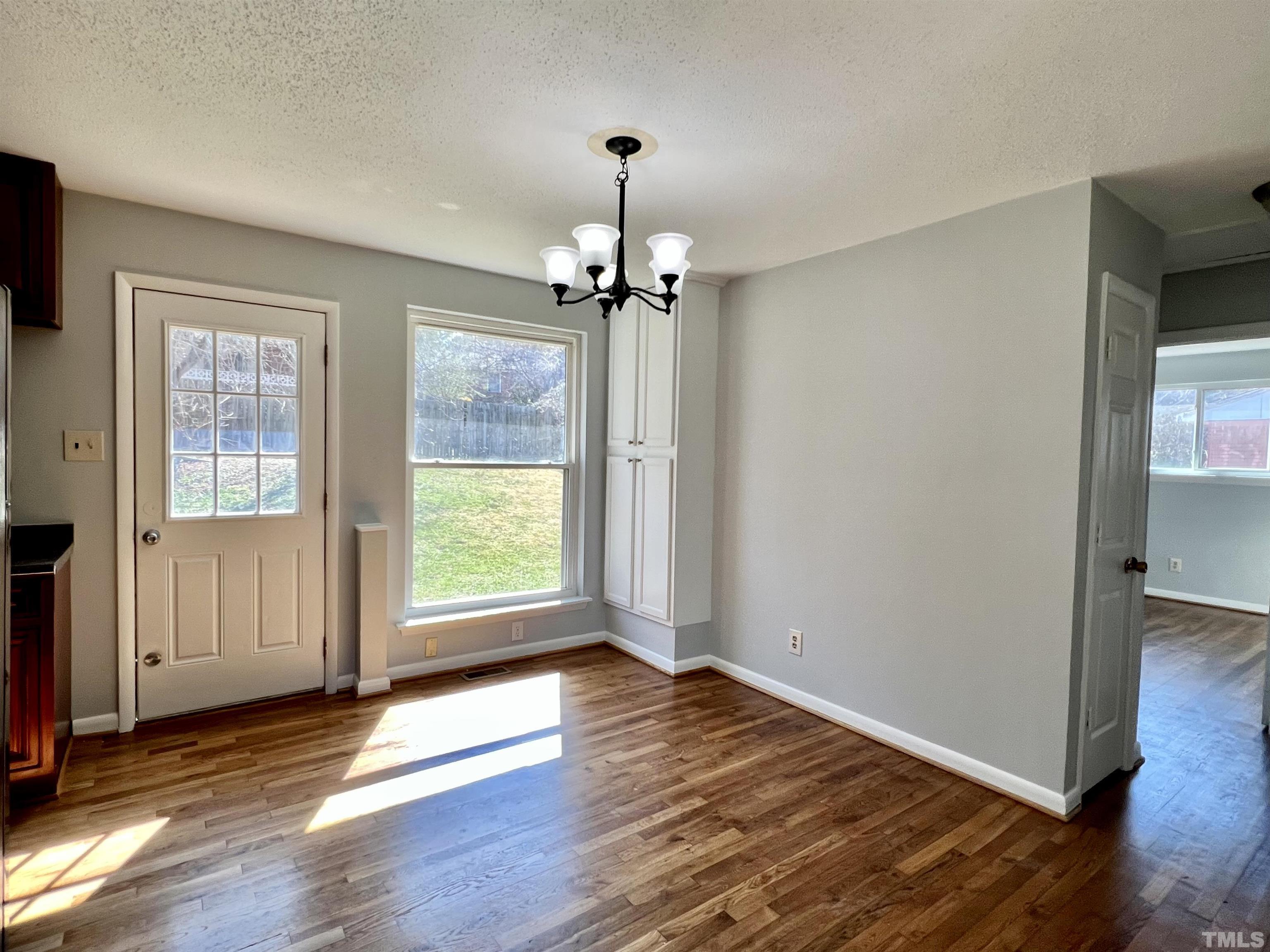 828 Newcombe Road Raleigh, NC 27610 - Photo 14 of 24 an empty room with wooden floor a chandelier and windows