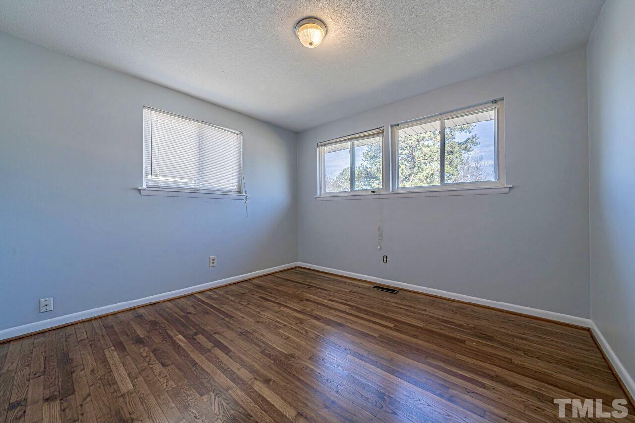 828 Newcombe Road Raleigh, NC 27610 - Photo 21 of 24 a view of an empty room with wooden floor and a window