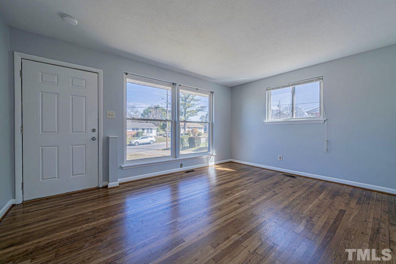 828 Newcombe Road Raleigh, NC 27610 - Photo 10 of 24 a view of an empty room with wooden floor and a window