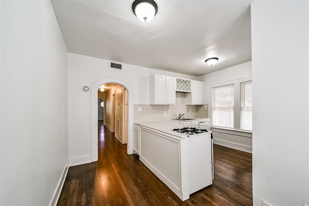 2235 Welch Street Houston, TX 77019 - Photo 11 of 18 a kitchen with stainless steel appliances granite countertop a stove a sink and white cabinets with wooden floor