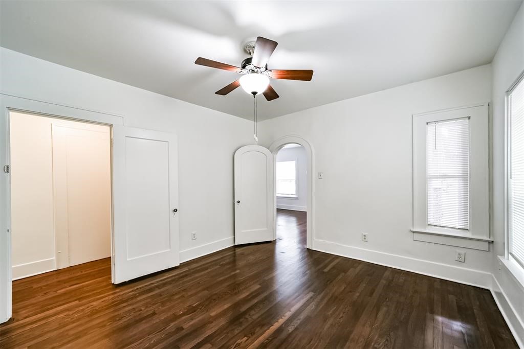 2235 Welch Street Houston, TX 77019 - Photo 14 of 18 an empty room with wooden floor chandelier fan and windows