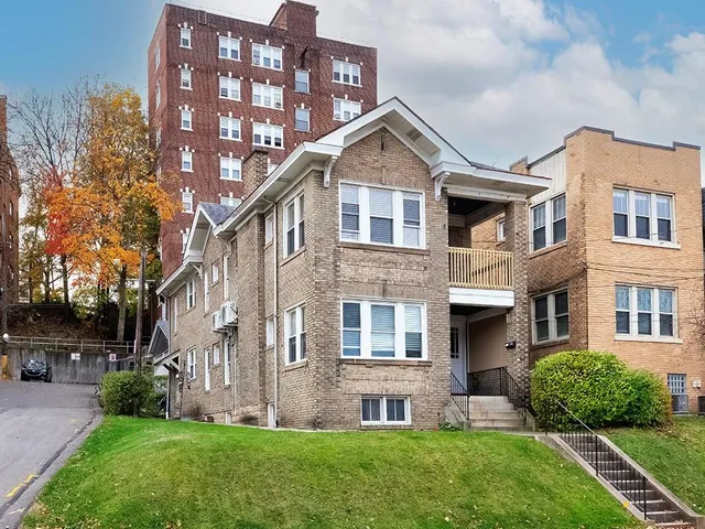 a front view of a house with a yard and green space