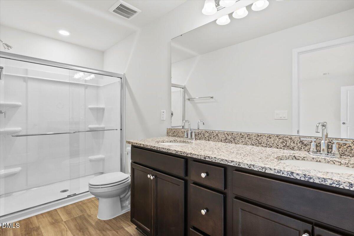 1387 Hasse Avenue Apex, NC 27502 - Photo 18 of 27 a bathroom with a granite countertop sink a toilet and shower