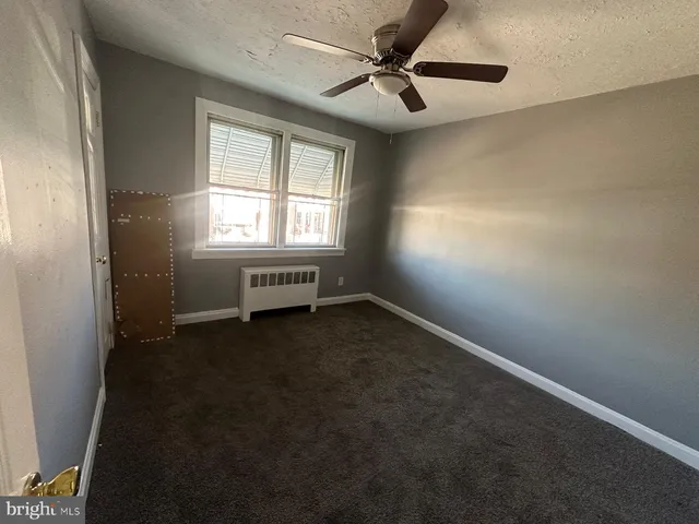 en empty room with windows and ceiling fan