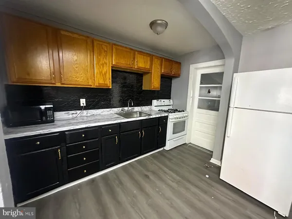 a kitchen with a sink a refrigerator a stove a oven cabinets and wooden floor