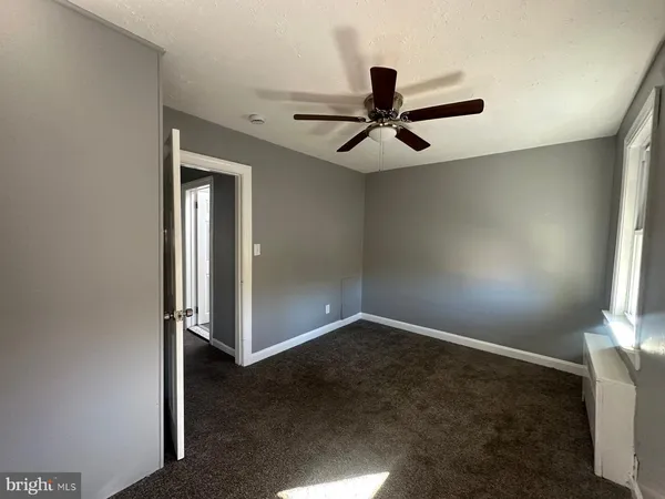 an empty room with windows and fan