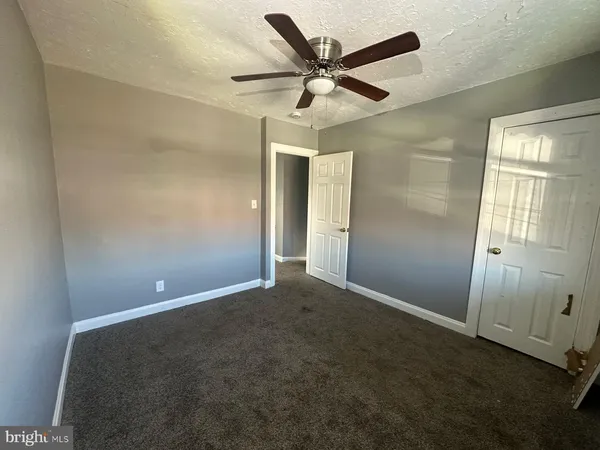 an empty room with ceiling fan and window