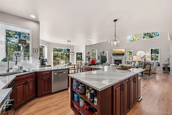 a living room with stainless steel appliances granite countertop a kitchen island a stove a sink a dining table and chairs with wooden floor
