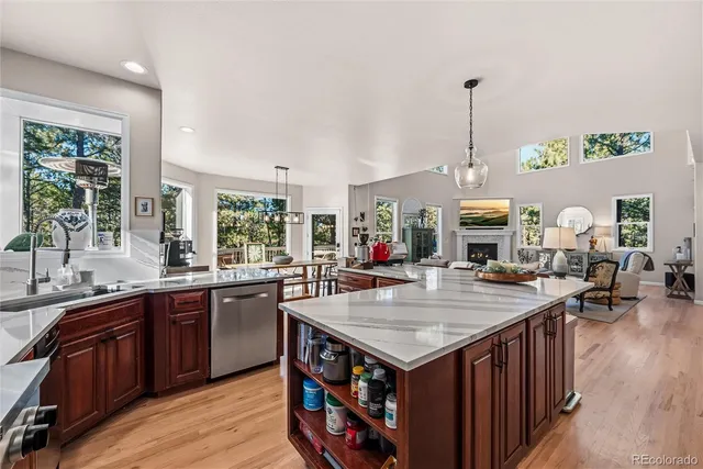 a living room with stainless steel appliances granite countertop a kitchen island a stove a sink a dining table and chairs with wooden floor