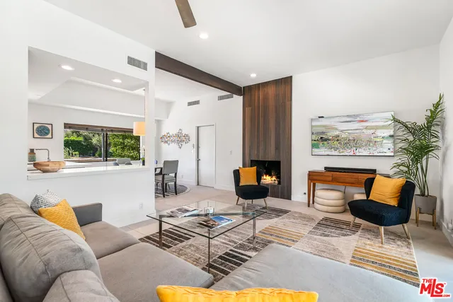 a living room with furniture kitchen view and a large window