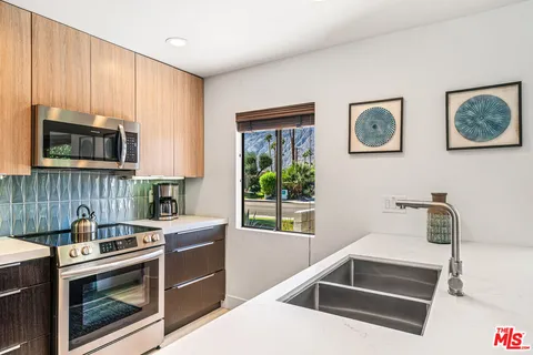 a bedroom with a bed lamp and a large window with balcony view