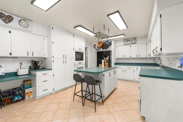 a kitchen with stainless steel appliances kitchen island granite countertop a refrigerator a sink a stove and white cabinets