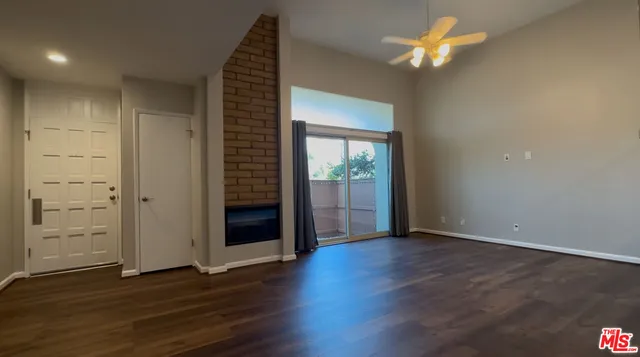 an empty room with wooden floor chandelier fan and windows