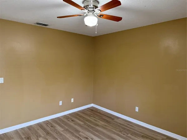 a view of a room with a ceiling fan and wooden floor