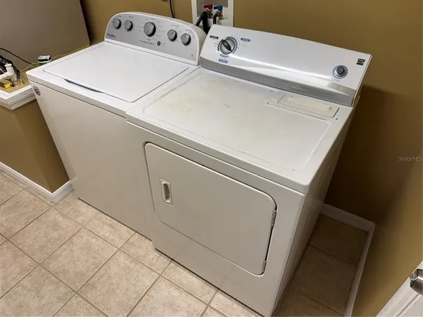 a close up view of washer and dryer with kitchen in the background