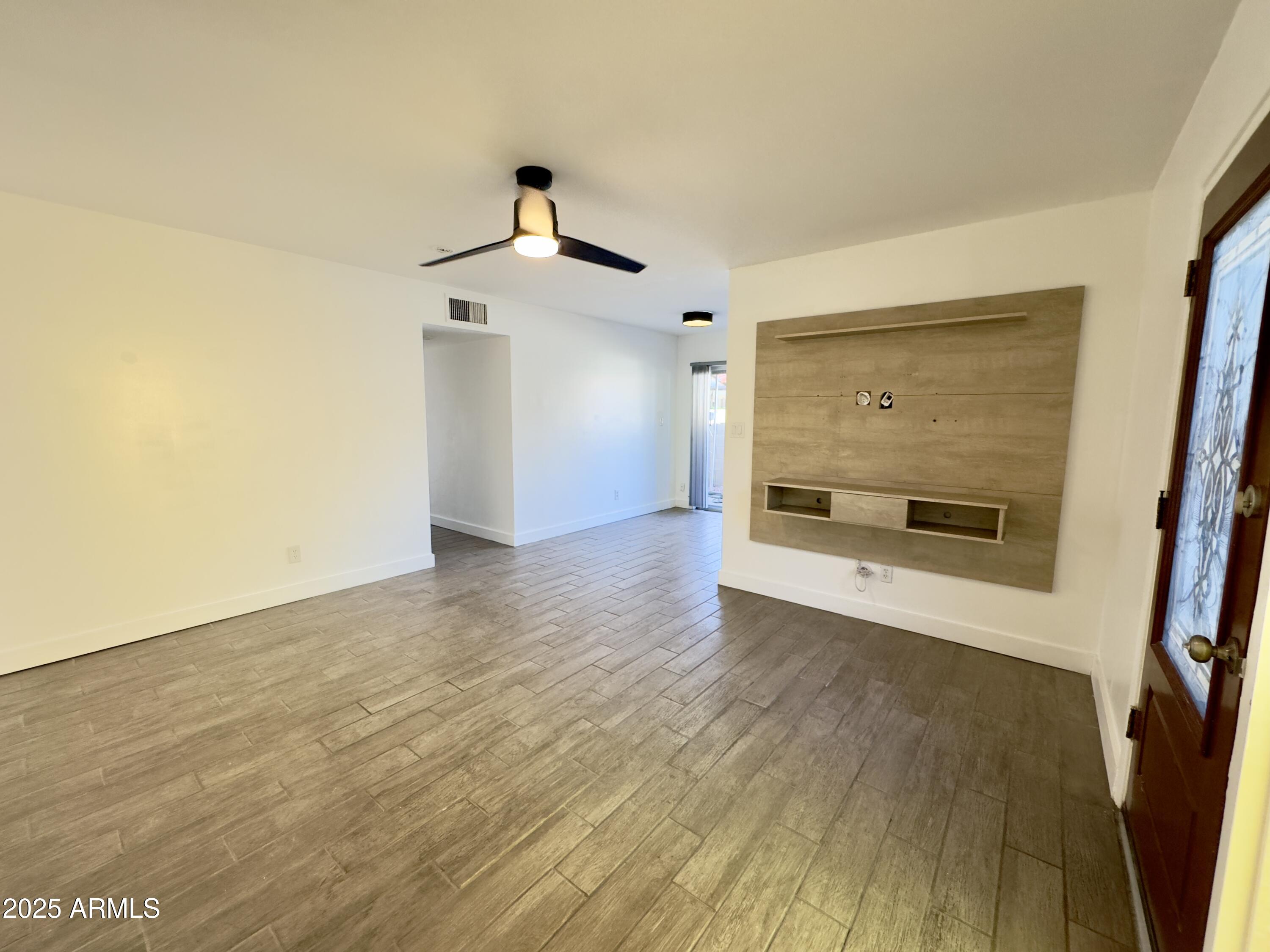 a view of an empty room with wooden floor and a window