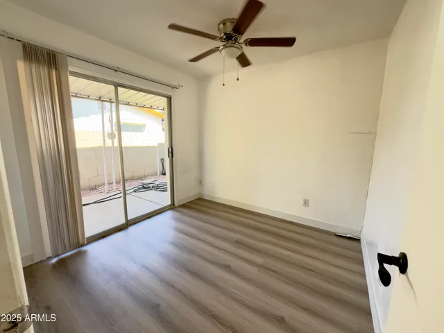 an empty room with wooden floor fan and windows