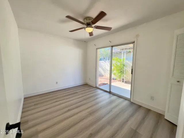 an empty room with wooden floor and fan