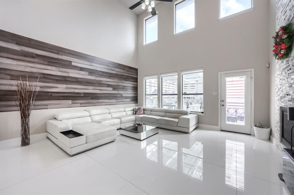 2246 Longview Road Irving, TX 75063 - Photo 15 of 40 Vaulted ceiling great room featuring full-height wood-finish accent wall, polished tile flooring, and a contemporary ceiling fan