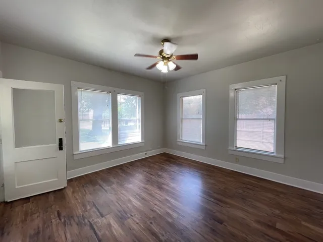a view of an empty room with a window and wooden floor
