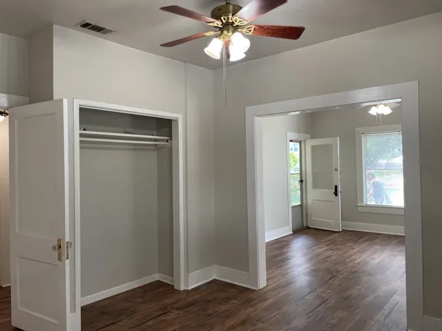 a view of an empty room with wooden floor and a window
