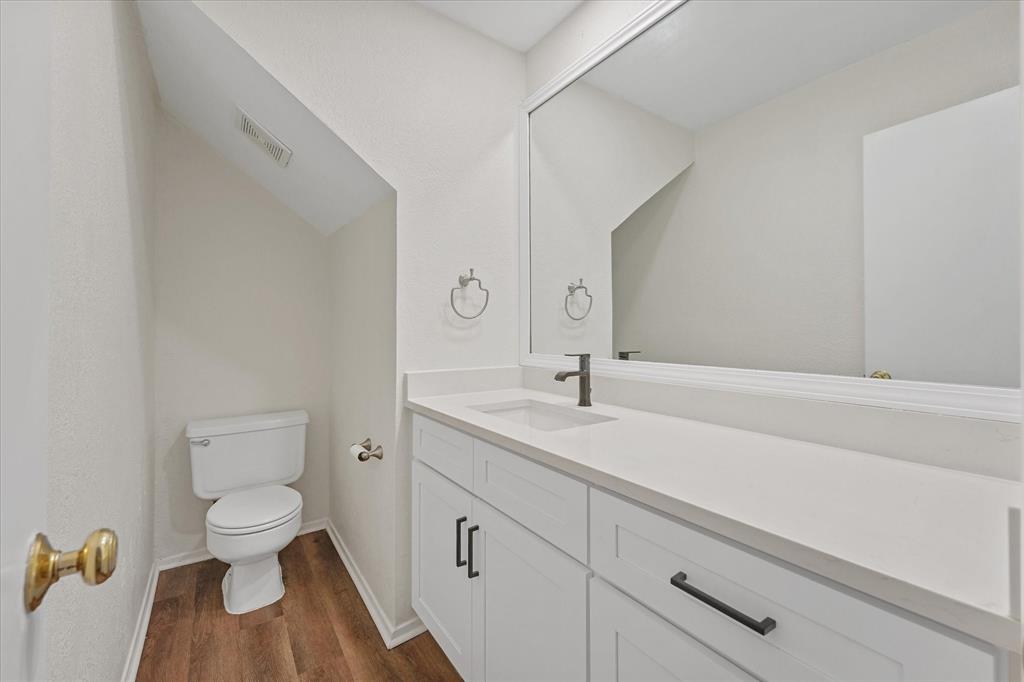 4005 Ridgebrook Drive Arlington, TX 76015 - Photo 9 of 18 Downstairs powder room featuring a white single vanity with a solid surface countertop, matte black faucet, and coordinating cabinet hardware