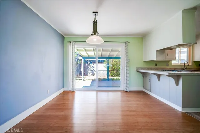 a kitchen with granite countertop wooden floors a sink stainless steel appliances and a window