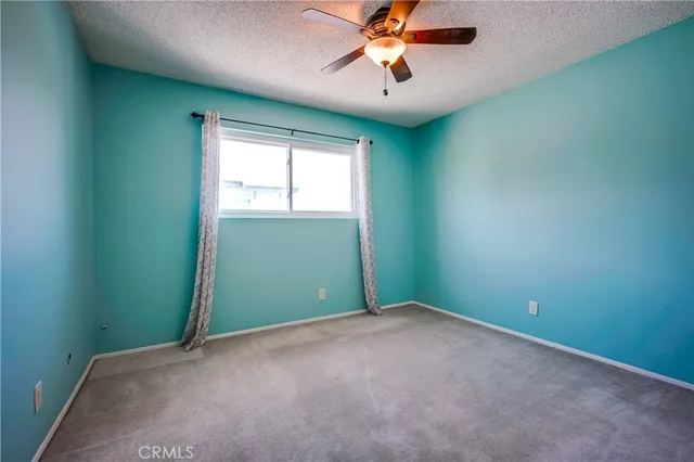 an empty room with a window and a fan
