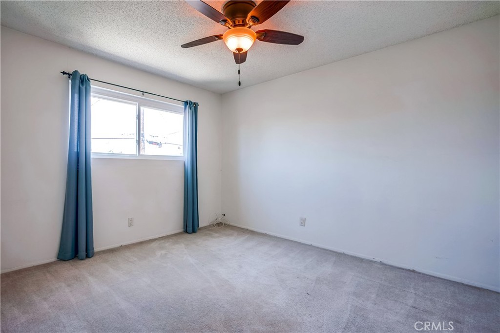 6473 Capistrano Way Riverside, CA 92504 - Photo 24 of 28 an empty room with windows and chandelier fan