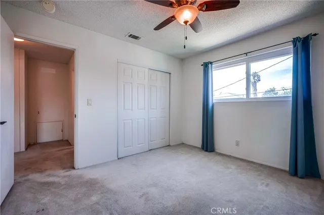 an empty room with a chandelier fan and windows