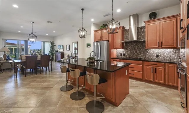 a kitchen with stainless steel appliances granite countertop a sink a stove a refrigerator a center island and chairs