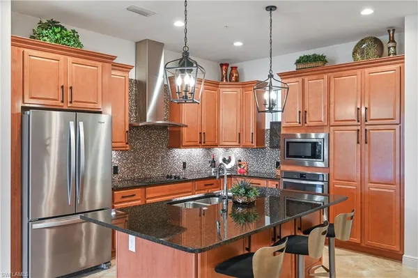 a kitchen with stainless steel appliances granite countertop a refrigerator a oven and a sink