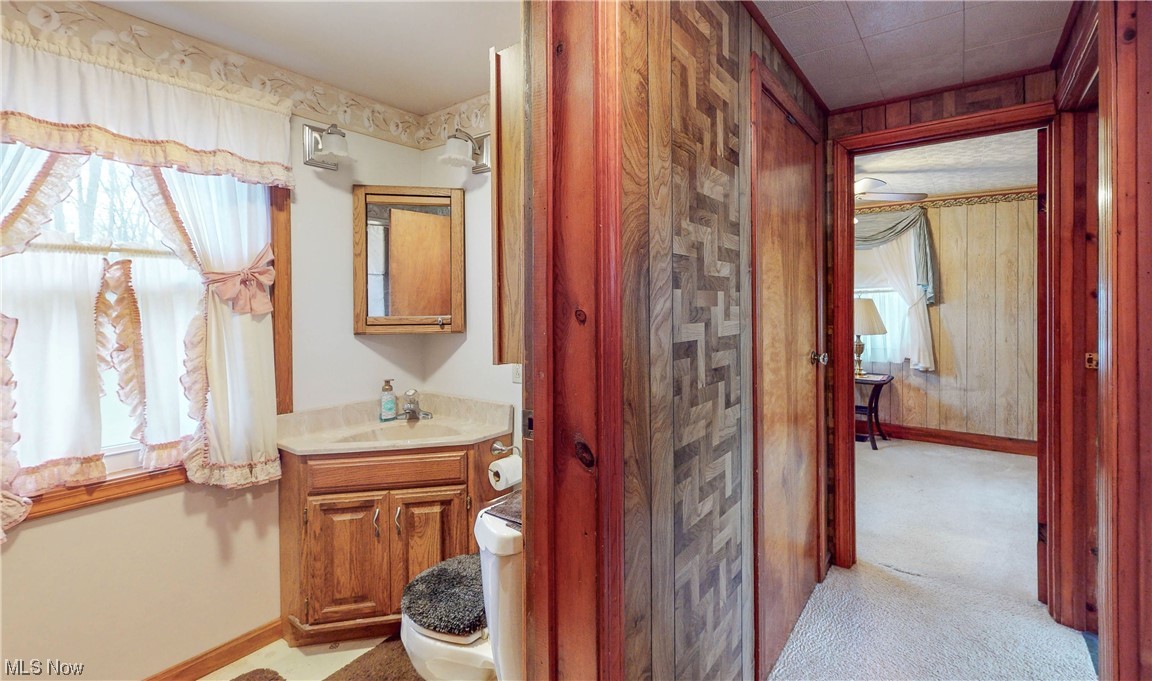 466 Pine Lake Road Sebring, OH 44672 - Photo 29 of 30 Bathroom with wood walls, toilet, and vanity with extensive cabinet space