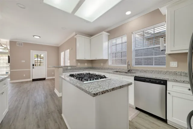 a kitchen with granite countertop a sink cabinets wooden floor and stainless steel appliances