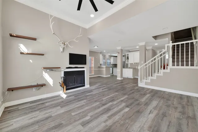 a view of a livingroom with a fireplace a ceiling fan and wooden floor