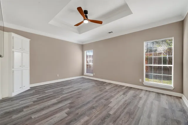 a view of empty room with wooden floor and ceiling fan