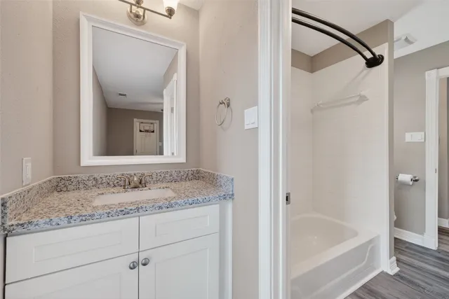 a bathroom with a granite countertop sink a mirror and a shower