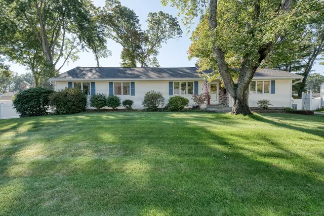 a view of a house with a big yard and large trees