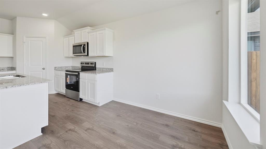 508 Wild Rose Way Princeton, TX 75407 - Photo 32 of 33 a kitchen with cabinets wooden floor and stainless steel appliances