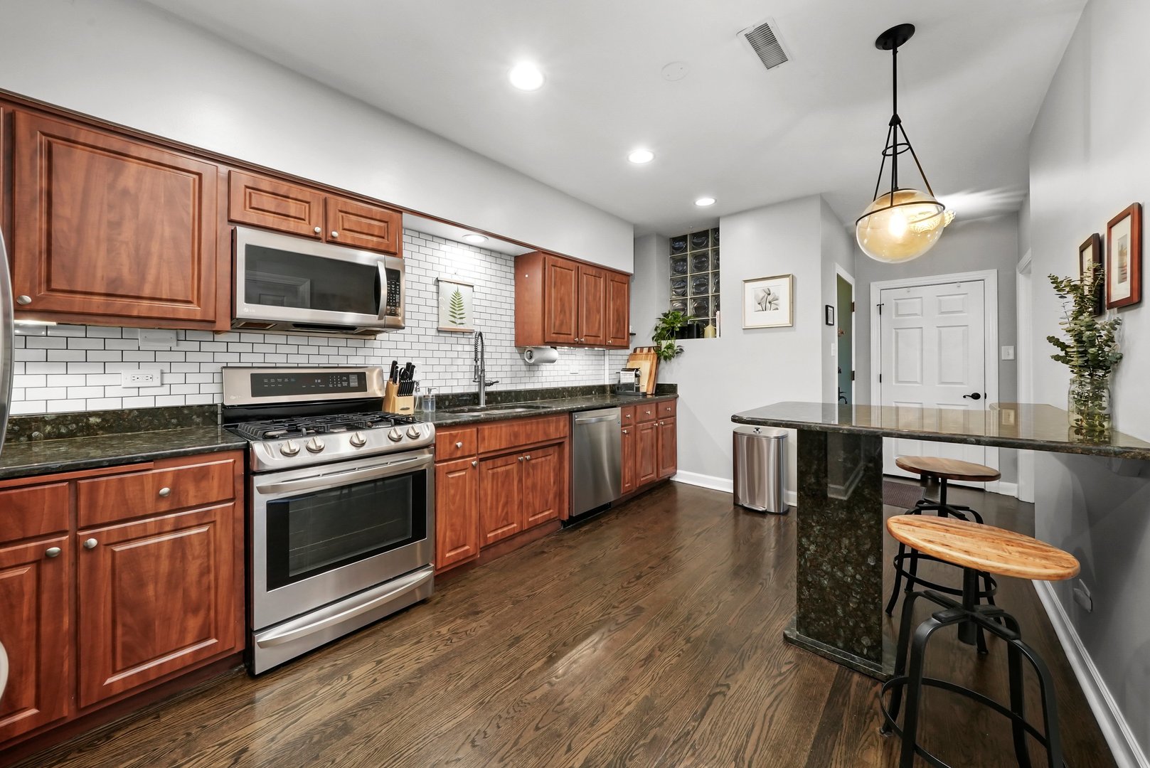 923 West Addison Street, Unit 2A Chicago, IL 60613 - Photo 3 of 9 a kitchen with stainless steel appliances granite countertop a stove top oven a sink dishwasher a dining table and chairs with wooden floor