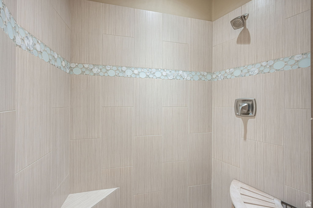 2331 West Entrada Trail, Unit 61 St. George, UT 84770 - Photo 48 of 69 Tiled shower stall featuring a decorative mosaic border, a built-in corner bench, and a mounted shower head with a separate control handle